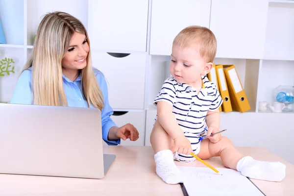 Mulher bonita com bebê trabalhando em casa — Fotografia de Stock