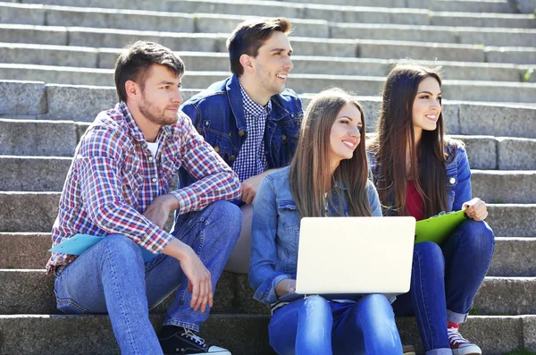 Šťastní studenti sedí na schodech v parku — Stock fotografie