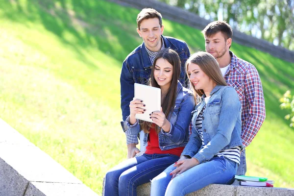 Šťastní studenti sedí v parku — Stock fotografie