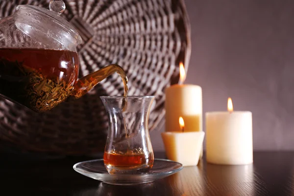 Té vertiendo en la taza de vidrio sobre fondo oscuro —  Fotos de Stock