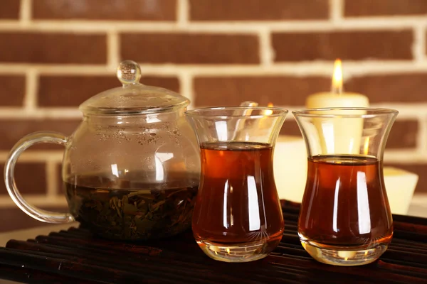 Komposition mit Tee in Tasse und Teekanne und Kerzen auf dem Tisch, auf Farbwandhintergrund — Stockfoto