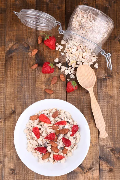 Healthy cereal with strawberry and nuts on wooden table — Stock Photo, Image