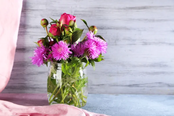 Mooie pioenrozen en korenbloemen in vaas op houten achtergrond — Stockfoto