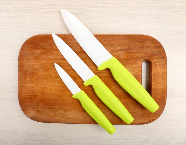 Köksknivar och skärbräda på träbord — Stockfoto