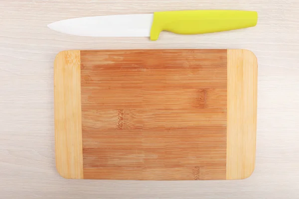 Kitchen knife and cutting board on wooden table — Stock Photo, Image