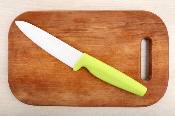 Kitchen knife and cutting board on wooden table — Stock Photo, Image