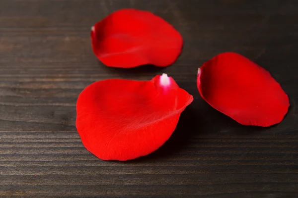 Schöne Blütenblätter roter Rosen auf hölzernem Hintergrund — Stockfoto