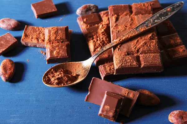 Cacao en polvo y chocolate negro sobre fondo de madera de color —  Fotos de Stock