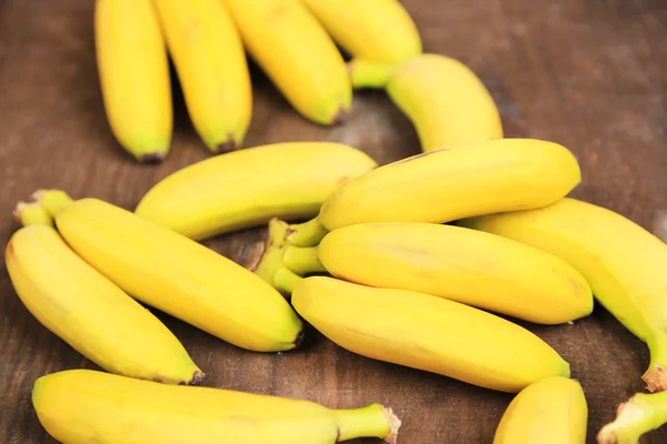 Bunch of mini bananas on color wooden background — Stock Photo, Image