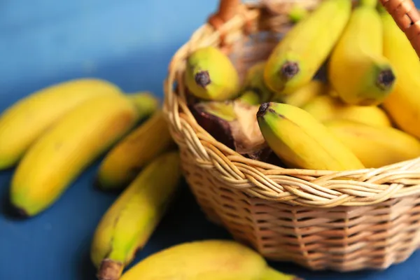 Lot de mini bananes dans panier en osier sur fond en bois de couleur — Photo