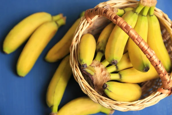 Ramo de mini plátanos en canasta de mimbre sobre fondo de madera de color —  Fotos de Stock