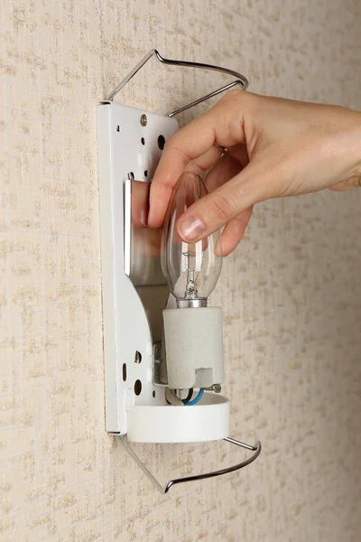 Hand changing light bulb at home