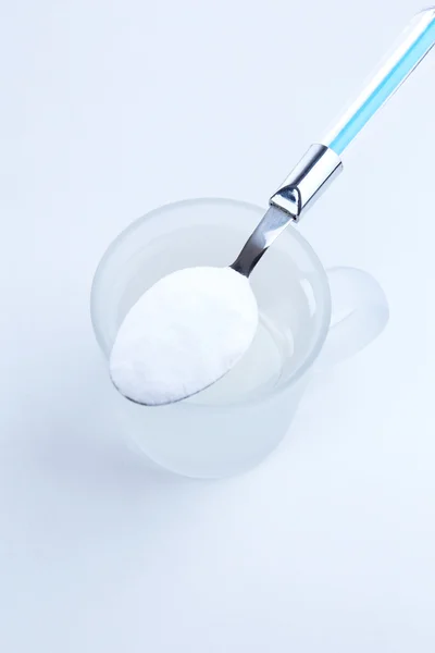 Spoon of baking soda over glass of water, isolated on white — Stock Photo, Image