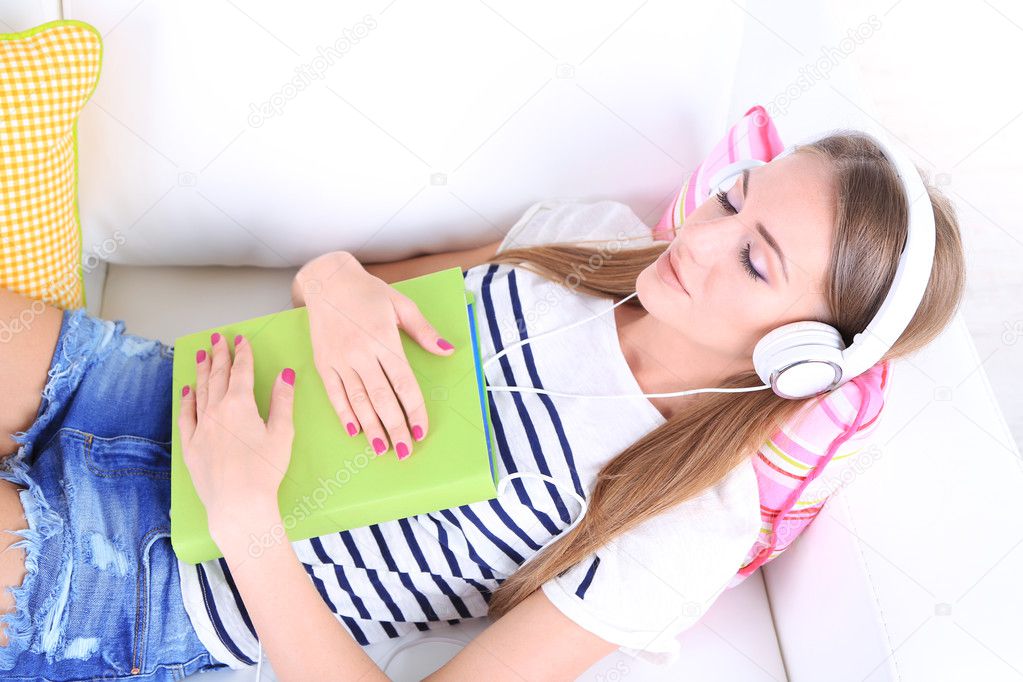 Conceptual image of  audio book. Beautiful girl with book and headphones.