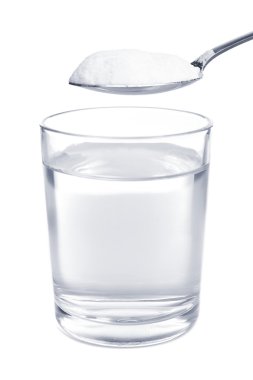 Spoon of baking soda over glass of water, isolated on white clipart