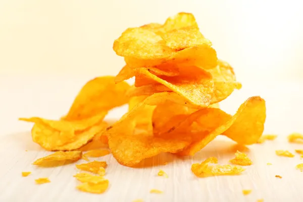 Haufen hausgemachter Kartoffelchips auf hellem Hintergrund — Stockfoto