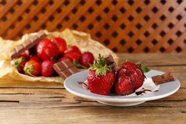 ahşap masa üstünde çikolata ile kırmızı olgun çilek