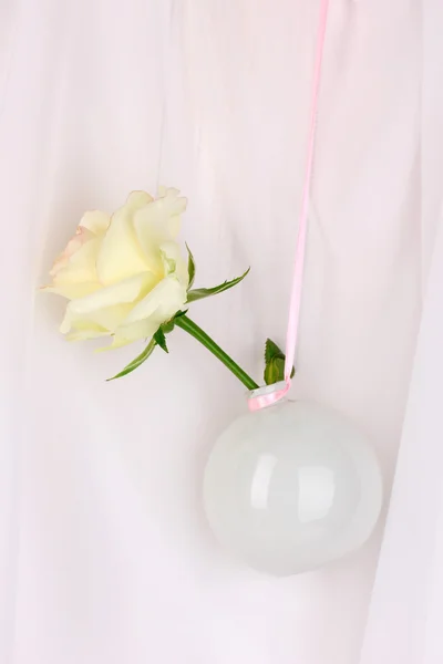 Mooie roos in een vaas opknoping op doek achtergrond — Stockfoto