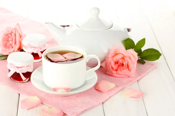 Tetera y taza de té con rosas y mermelada sobre mesa de madera blanca — Foto de Stock