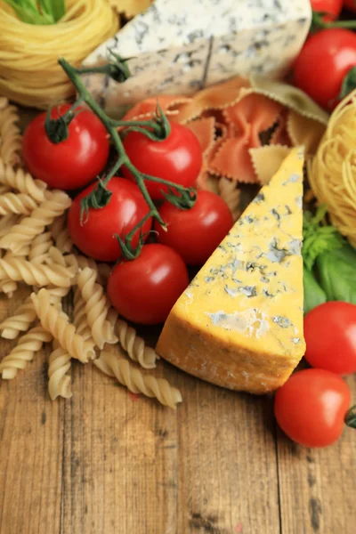 Verschiedene Nudeln, Käse und Tomaten auf Holztisch in Großaufnahme — Stockfoto