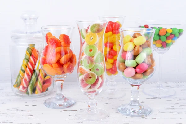 Verschillende kleurrijke vruchten snoep in bril op tabel op lichte achtergrond — Stockfoto