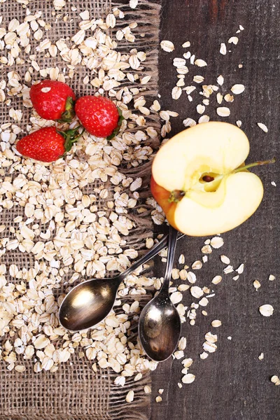 Apel dan stroberi dengan oatmeal dan sendok vintage, pada latar belakang kayu warna — Stok Foto