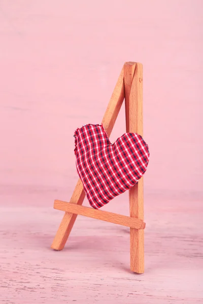 Vakkert hjerte, lite dekorativt staffeli med rosa bakgrunn – stockfoto