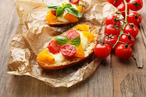 Sabrosa bruschetta con tomates, sobre una vieja mesa de madera —  Fotos de Stock