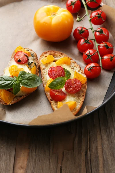 Smakelijke bruschetta met tomaten op pan, op oude houten tafel — Stockfoto