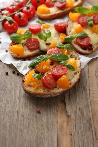 Sabrosa bruschetta con tomates, sobre una vieja mesa de madera — Foto de Stock