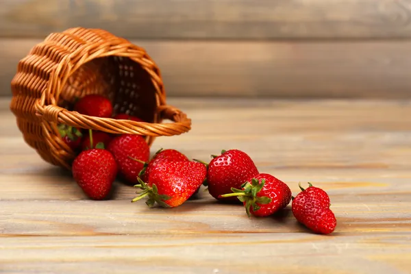 Red ripe strawberries in wicker basket on wooden background — Stock Photo, Image