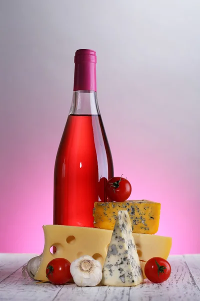 Vinho rosa e diferentes tipos de queijo no fundo colorido — Fotografia de Stock