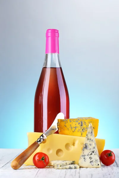 Pink wine and different kinds of cheese on colorful background — Stock Photo, Image