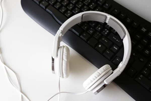 Headphone and keyboard close-up on white desk background — Stock Photo, Image