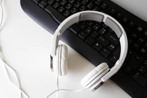 Primer plano de auriculares y teclado sobre fondo de escritorio blanco — Foto de Stock