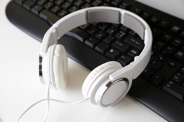 Headphone e teclado close-up no fundo da mesa branca — Fotografia de Stock