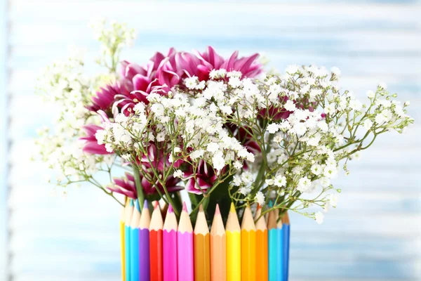 Beautiful flowers in colorful pencils vase on wooden background — Stock Photo, Image