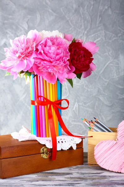 Beautiful flowers in colorful pencils vase on grey background — Stock Photo, Image