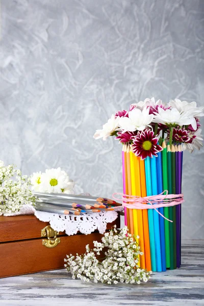 Beautiful flowers in colorful pencils vase on grey background — Stock Photo, Image