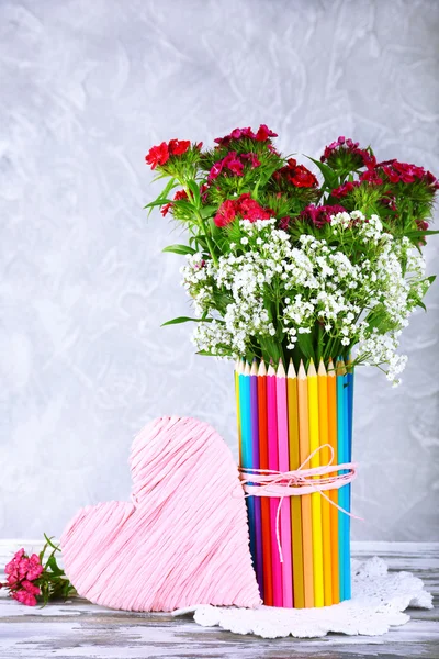 Vackra blommor i färgglada pennor vas på grå bakgrund — Stockfoto
