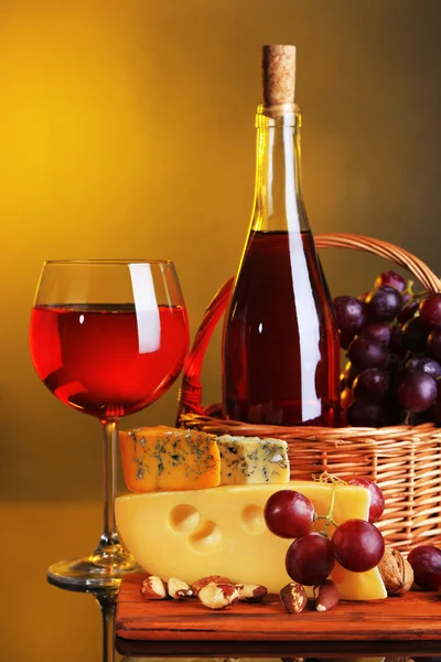 Rózsaszín bor, a szőlő és a sajt-színes háttérrel — Stock Fotó
