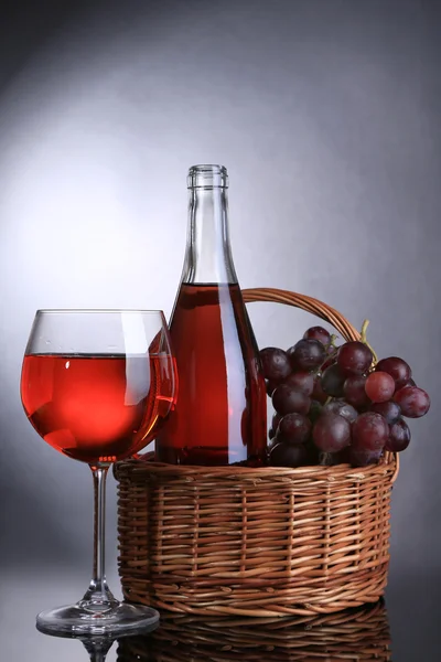 Ripe grapes, wine glass and bottle of wine on grey background — Stock Photo, Image