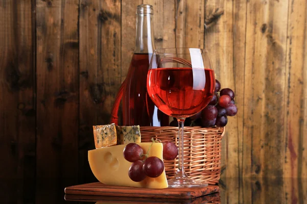 Pink wine, grapes and cheese on wooden background — Stock Photo, Image