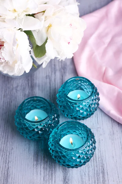 Glass candlesticks and flowers on color wooden background — Stock Photo, Image