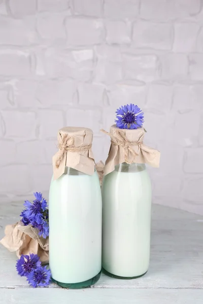 Bottles of milk and cornflowers on wooden table — Stock Photo, Image