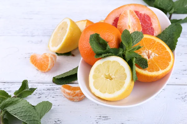 新鲜的柑橘类水果，绿色的叶子在碗上木制的背景 — 图库照片