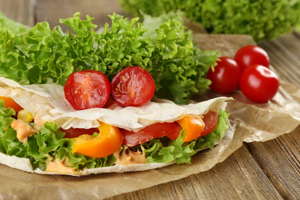 Enveloppement végétarien rempli de poulet et de légumes frais sur une table en bois, fermer — Photo