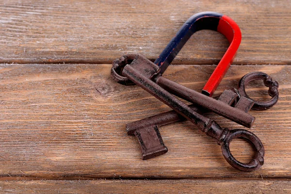 Ímã com chaves antigas no fundo de madeira — Fotografia de Stock