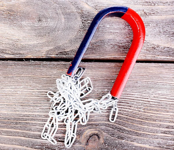 Magnet and  chain on color wooden background — Stock Photo, Image