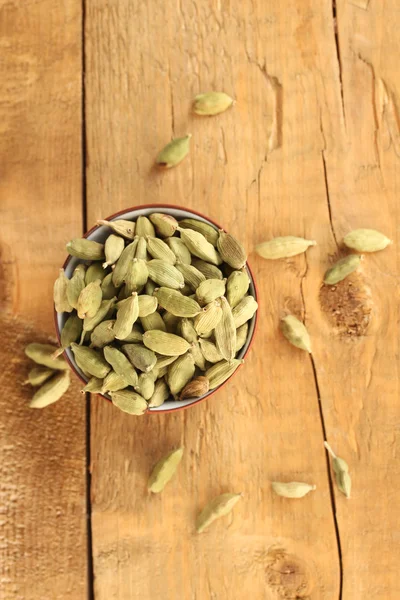 Green cardamom in ceramical bowl on wooden background close-up — Stock Photo, Image